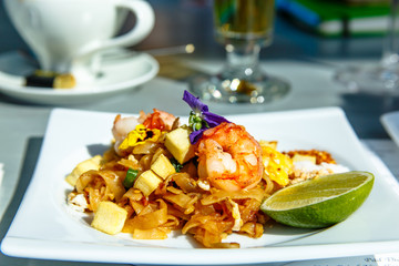 Prawn noodles lying on a plate and decorated with edible flowers, Thai cuisine