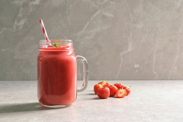 Mason jar with tasty strawberry smoothie on table