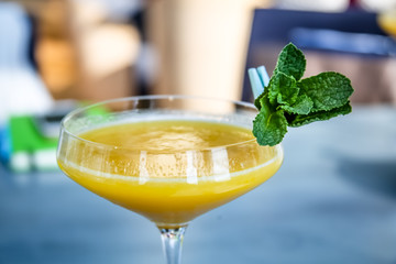 Yellow mango cocktail with mint leaf in a glass.
