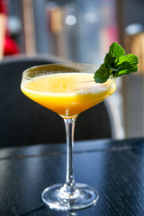 Yellow mango cocktail with mint leaf in a glass.