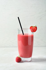 Glass with tasty strawberry smoothie on table