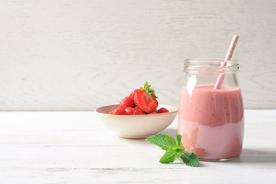 Glass jar with tasty strawberry smoothie on table