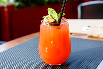 Orange lemonade with passion fruit in a glass on the restaurant table.