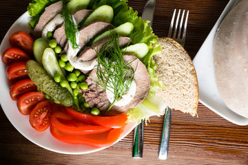 boiled tongue with vegetables tomatoes red pepper cucumber lettuce peas with mayonnaise with wooden...