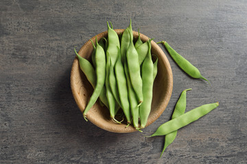 Plate with fresh green beans on wooden table, top view
