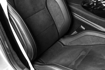 Modern Luxury car inside. Interior of prestige modern car. Comfortable leather seats. Black perforated leather with stitching. Steering wheel and dashboard. automatic gear stick shift. Black and white