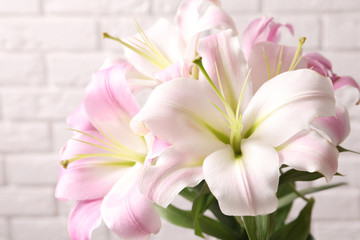 Beautiful blooming lily flowers on brick wall background