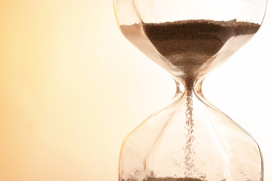 Hourglass with flowing sand on light background, closeup. Time management