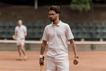 retro styled tennis player walking with racket at court