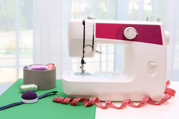 Modern sewing machine on table near window indoors