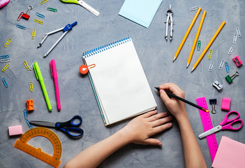 Back to School: Stationery and children's hands on a dark table.