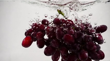 Slow motion video of red grapes. Bunch of grapes are immersed in water with bubbles. - Powered by Adobe