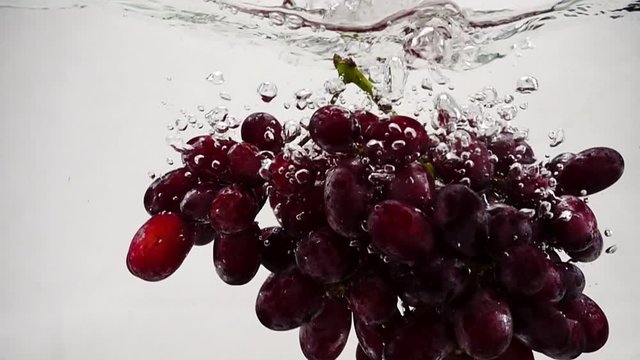 Slow motion video of red grapes. Bunch of grapes are immersed in water with bubbles.