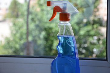 Woman cleaning a window with cleaning sprayer.