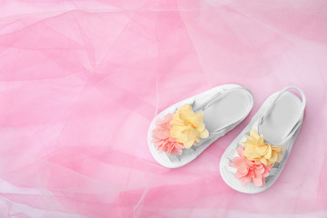 Fototapeta na wymiar Pair of cute baby sandals on color fabric, top view