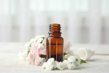 Fototapeta na wymiar Bottle of essential oil and flowers on table