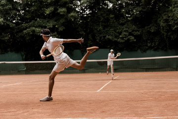 retro styled men playing tennis at court
