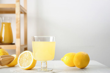 Glass with fresh lemon juice and fruits on table