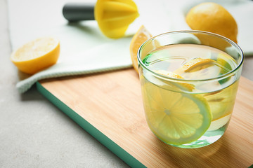 Glass of water with lemon slice on wooden board