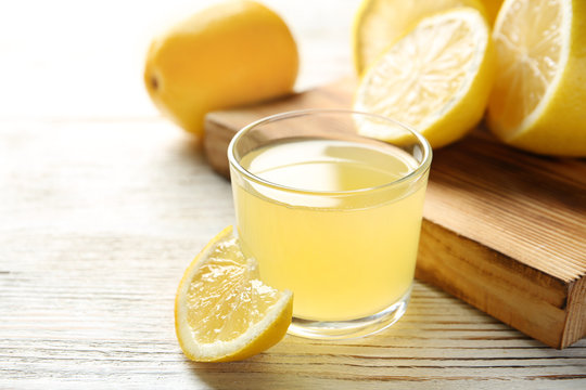 Glass with fresh lemon juice and fruits on table