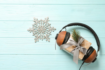 Fototapeta na wymiar Flat lay composition with gift box and headphones on wooden background. Christmas music concept