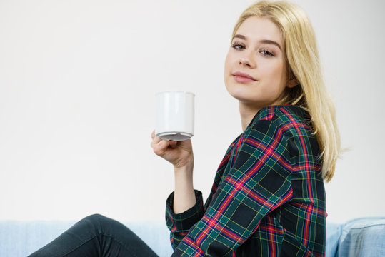 Teenage woman sitting on sofa with mug