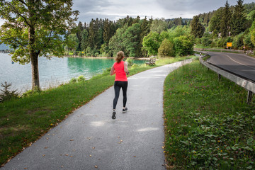 Young woman running along lake side path