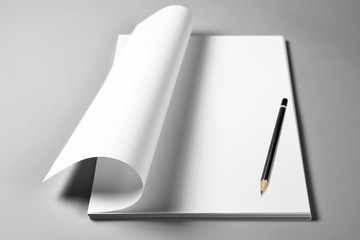 Pile of blank sheets of paper with curled upper page and pencil 