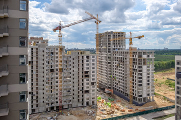 Two unfinished multi-storey houses and three  building cranes on the new construction