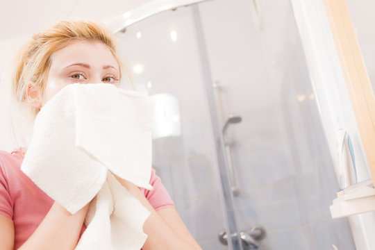 Woman with white towel wiping face after cleaning
