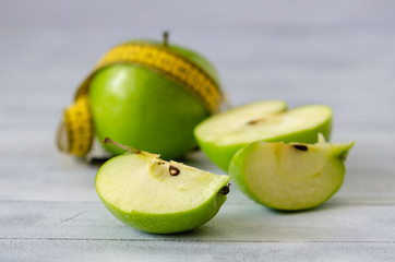  Green apple with measuring tape  on white wooden background.Dieting concept.