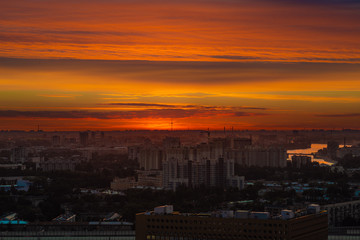 Fototapeta na wymiar City during warm sunset. Cityscape panorama at summer sunset. Orange sky on sunset in big city. Saint-Petersburg skyline in sunset, Russia.