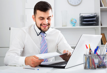 Young male worker working productively on project in office