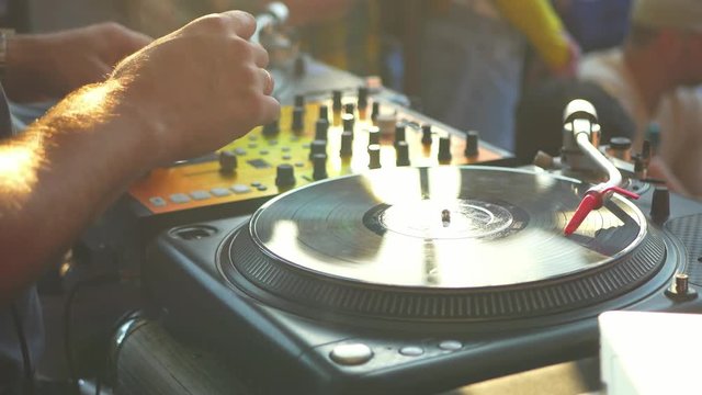 close up dj hand scratching vinyl record on turntable on a party