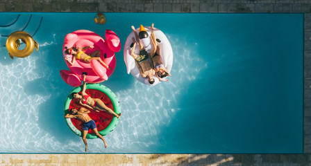 Friends relaxing on inflatable mattresses in pool