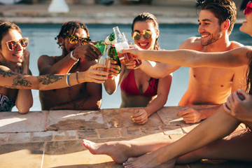 Group of friends toasting beer in a pool party