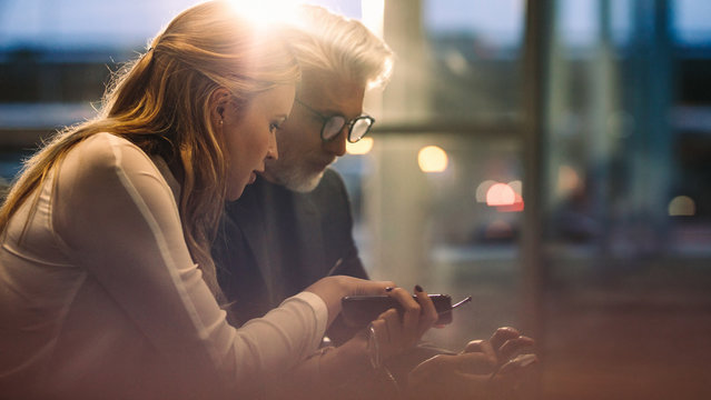 Business Professionals Using Cell Phones In Office Lobby