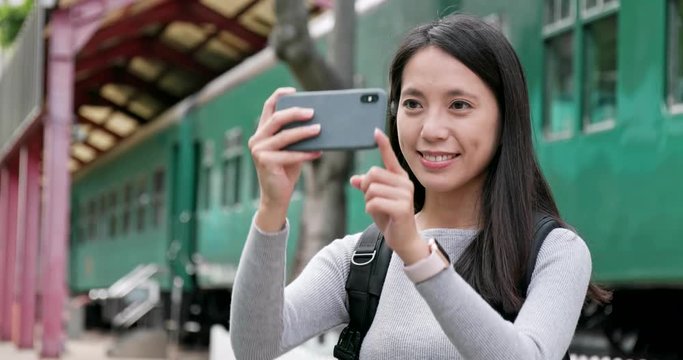 Woman traveler using smart phone for taking photo and video