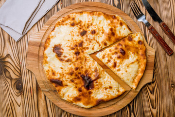 Ossetian pie with cheese on wooden background