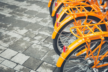 A row of bright orange bikes parked on stone