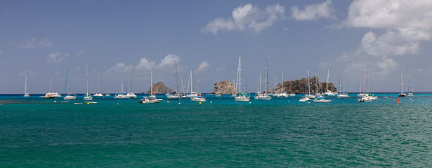 Obraz premium Multiple sailboats anchored in the Caribbean with small islands in background