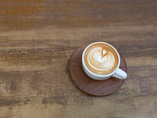 Beautiful cup of cappuccino with trendy latte art on the wooden background