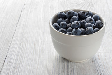 background. blueberry in a white cup on a wooden white table
