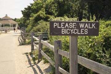 Fototapeta na wymiar Signage to please walk bicycles on pedestrian path at a park