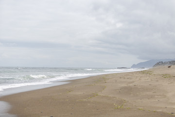 Ocean shore. Diagonal positioning. Hazy background. Full cloud cover.