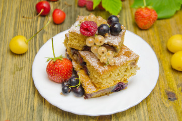 pieces of cake with berries and fresh strawberry currant and cherry berries on wooden background 