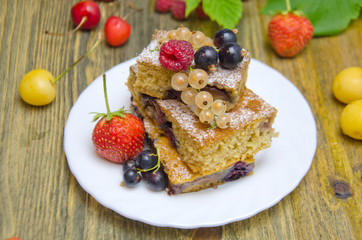 pieces of cake with berries and fresh strawberry currant and cherry berries on wooden background