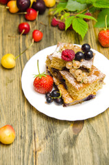 pieces of cake with berries and fresh strawberry currant and cherry berries on wooden background 