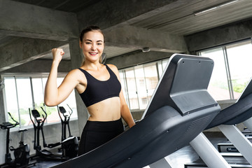 Fototapeta na wymiar Cute young woman exercising on treadmill at a gym.Active young woman running on treadmill. smile and funny emotion.