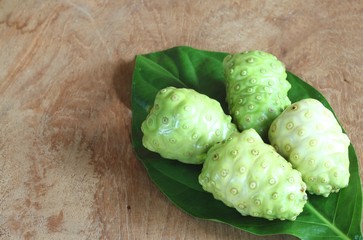 Noni fruit and Noni slice with leaf on old wooden table.Vegetable and Herb